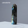 A dark blue labradorite crystal point prism tower displayed on a white surface.