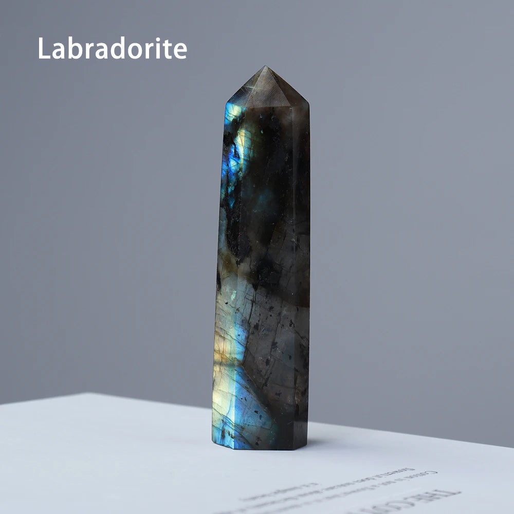 A dark blue labradorite crystal point prism tower displayed on a white surface.