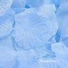 Light blue silk rose petals scattered on a surface.