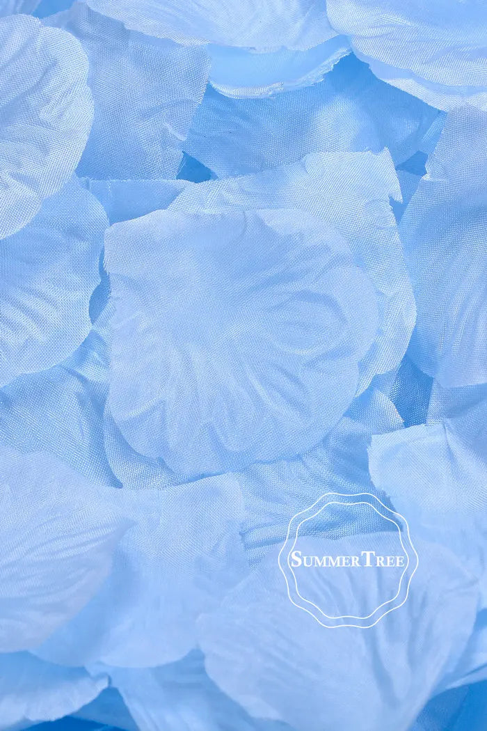 Light blue silk rose petals scattered on a surface.
