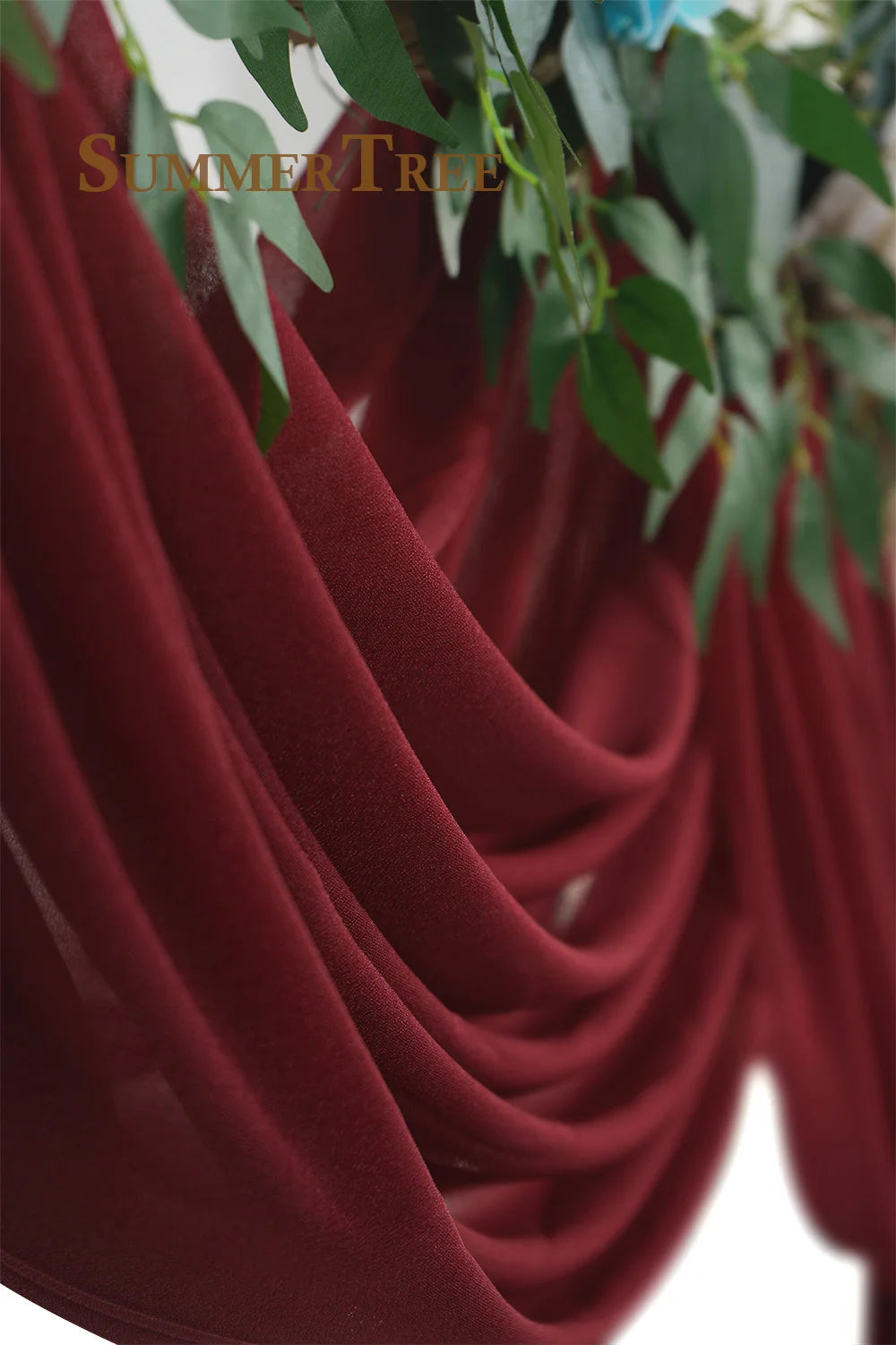 Deep burgundy chiffon fabric draped elegantly, used as a wedding arch backdrop.