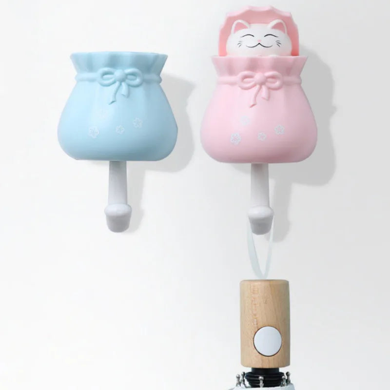 Two pink and blue cartoon cat wall hooks with wooden hangers for organization
