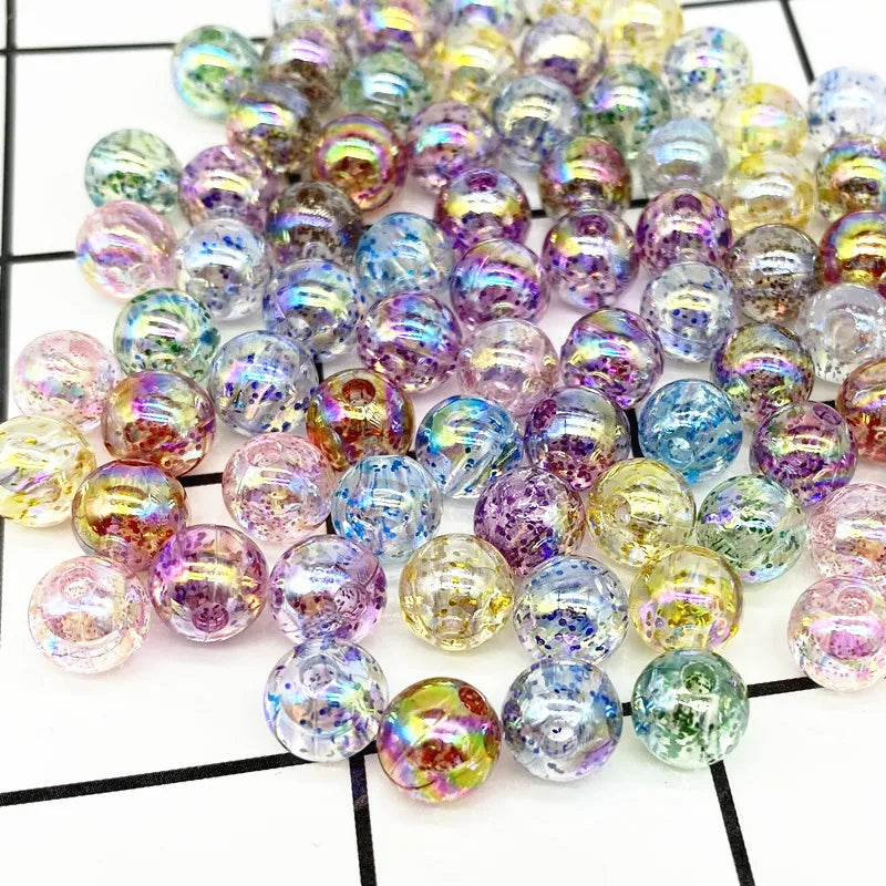 A collection of iridescent round acrylic beads in various shades of purple, green, and blue for jewelry making