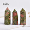 Three unakite crystal point prisms of varying shades of green and pink resting on a white surface.