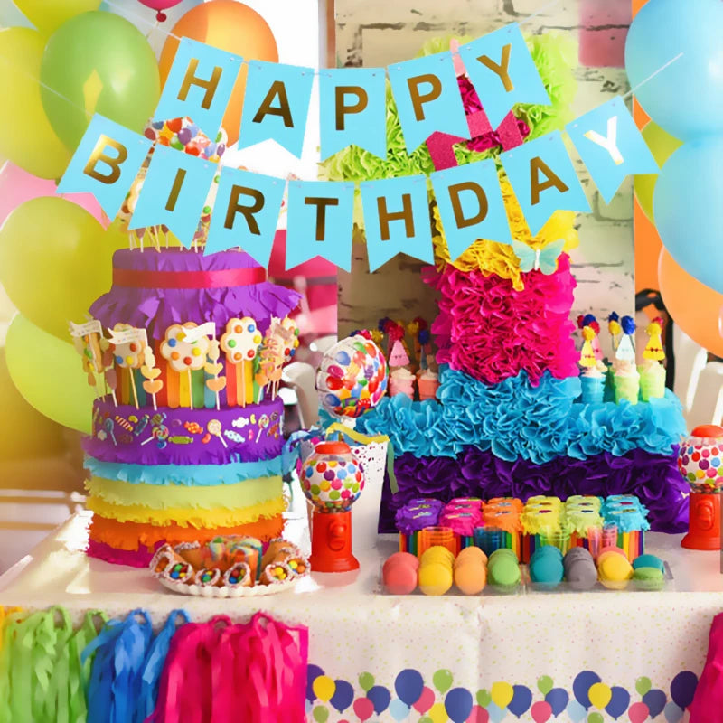 Una colorida celebración de cumpleaños con pastel de varios niveles, globos y un letrero decorativo.