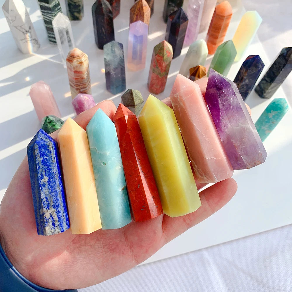 A hand holds a collection of colorful natural crystal points and prisms for meditation and home decor.