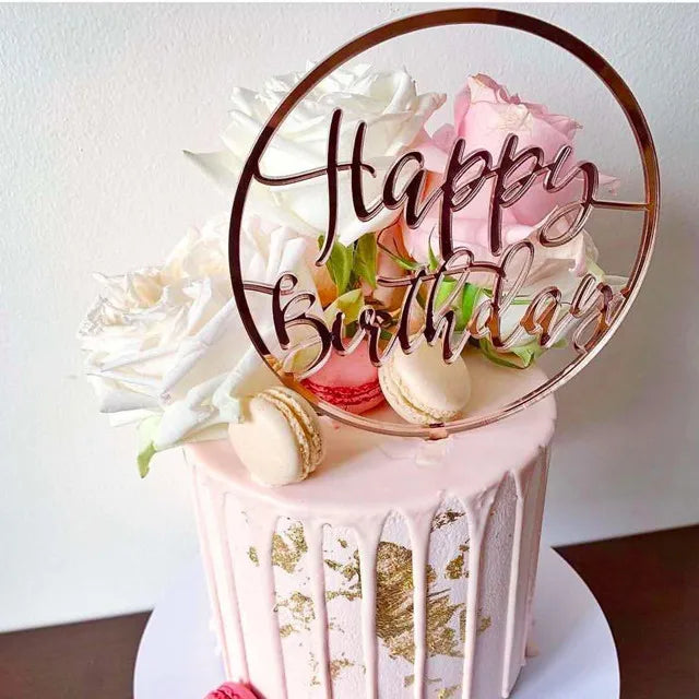 كعكة عيد ميلاد وردية بتصميم ورقة ذهب ومزينة بقطعة أكريليك دائرية تحمل عبارة عيد ميلاد سعيد