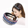 A woman is wearing a black crystal rhinestone headband on her hair.