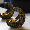 A black resin crescent incense burner with gold detailing is shown smoking on a white surface.