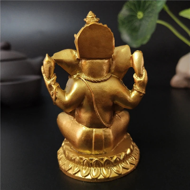 A handcrafted gold resin statue of Ganesha sitting on a lotus base.