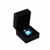 A black box containing a blue optical glass prism cube with rainbow light inside.