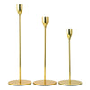 A set of three gold-toned European style iron candle holders with slender stems and round bases.