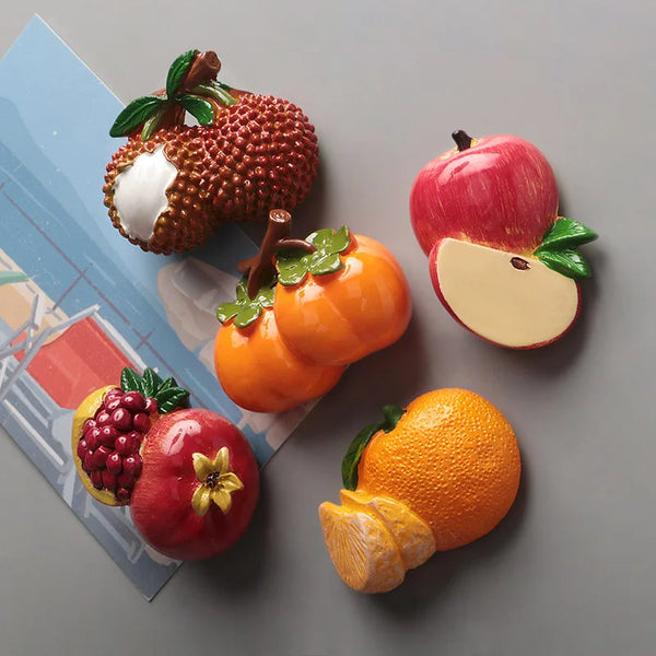 A set of realistic fruit and vegetable fridge magnets including a textured pumpkin, apple, orange, and pomegranate on a blue 