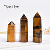 Three natural crystal point prisms in varying shades of amber and brown stacked on a white surface.