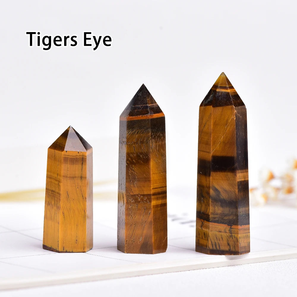 Three natural crystal point prisms in varying shades of amber and brown stacked on a white surface.