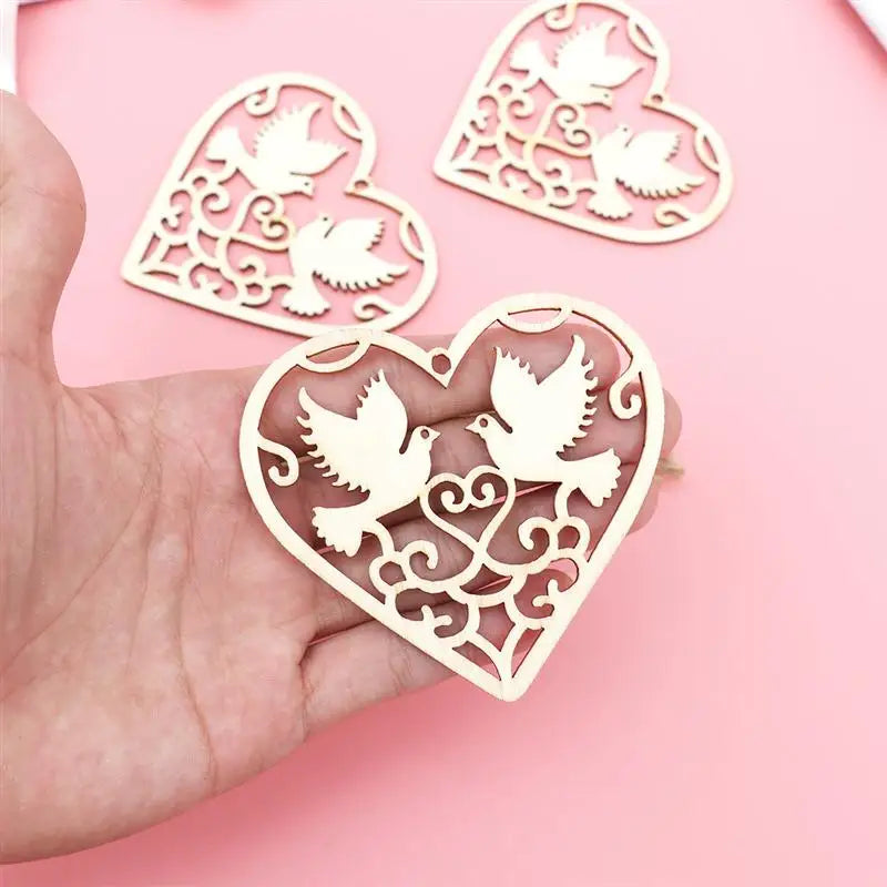A hand holds a set of ten wooden heart-shaped hanging ornaments featuring delicate bird cutouts.