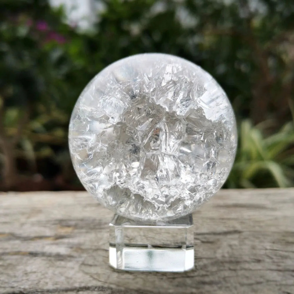 A clear, spherical crystal ball water feature ornament resting on a glass stand.