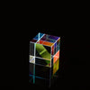 A transparent cube filled with colorful optical glass prisms reflecting light on a dark surface.