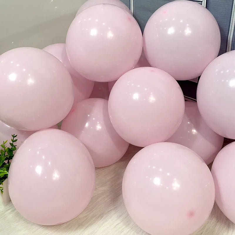 A collection of light pink pastel candy balloons arranged on a white surface.