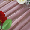 A close-up of pink chiffon fabric draped in vertical folds, with a white rose and green leaves visible.