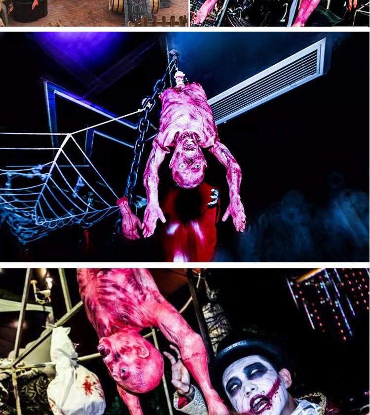 A person dressed as a bloody, monstrous figure hangs from wires in a dark, spooky environment.