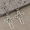 Silver stainless steel cross pendant featuring praying hands design resting on a gray stone surface