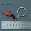 A red miniature alloy gun model keychain with a silver split ring attached, shown next to a ruler.