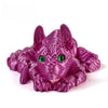 A vibrant purple articulated sphynx cat figurine with large green eyes, posed for desk decor.