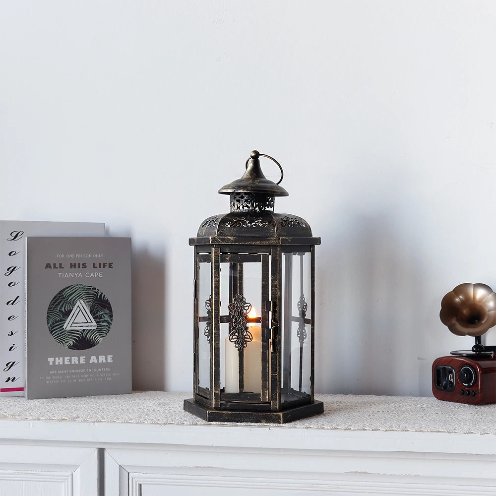 A vintage Nordic iron candle lantern with glass panes sits on a white shelf next to a book.