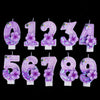 A set of nine glitter flower number candles from zero to nine arranged in a row.