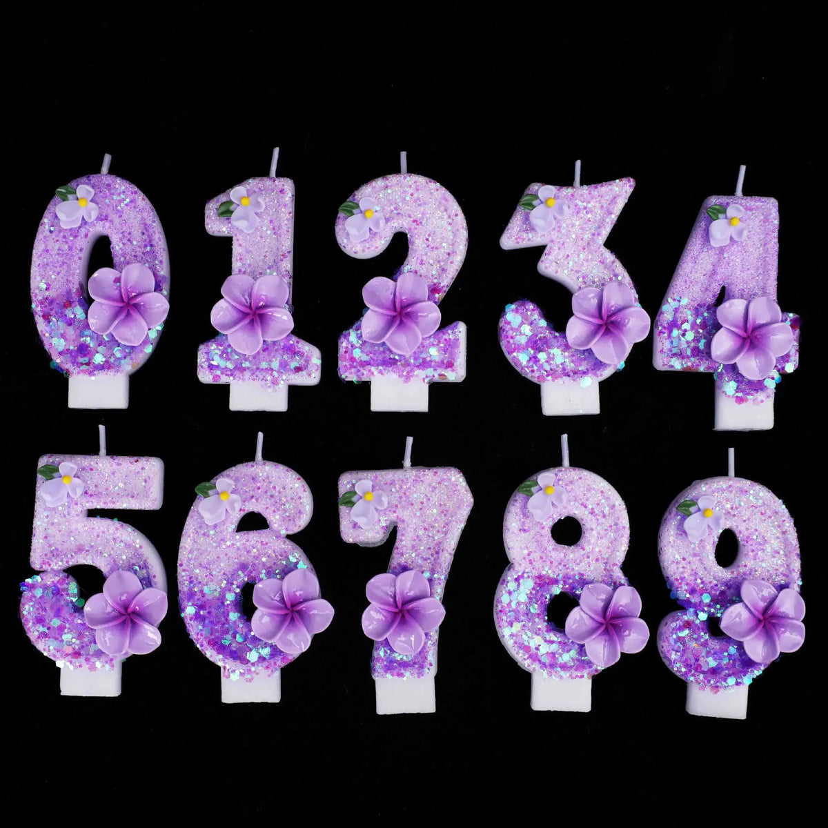 A set of nine glitter flower number candles from zero to nine arranged in a row.