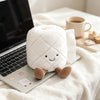 A white plush toy shaped like a toilet paper poop plunger with a smiling face resting on a laptop.