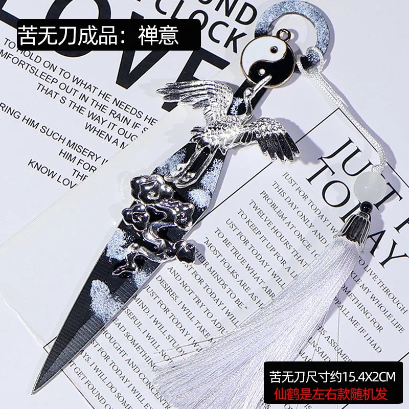 A silver utility knife with a decorative black yin-yang charm and feather design, set against a dark background.