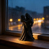 A dark romantic sculpture of a Gothic Grim Reaper couple embracing, displayed on a windowsill.