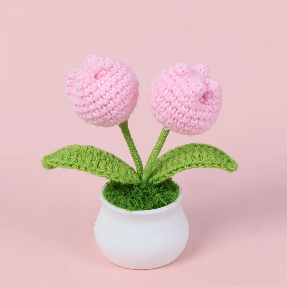 Hand woven pink crochet flowers in green leaves potted in a white ceramic vase