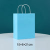 A light blue paper gift bag with white handles, shown against a dark teal background.