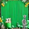 A vibrant green pleated backdrop decorated with yellow and lime green foliage and small stuffed animals.