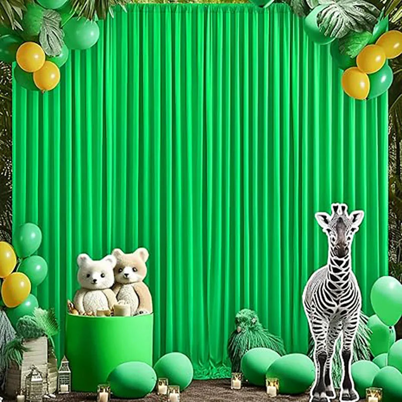A vibrant green pleated backdrop decorated with yellow and lime green foliage and small stuffed animals.