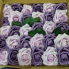 A box filled with artificial real touch foam roses in shades of purple and pink.