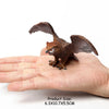 A realistic figurine set of an owl, vulture, and bald eagle perched on a human hand.