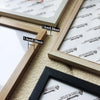 Close-up of wooden photo frames showing measurements and various wood tones for wall decor.