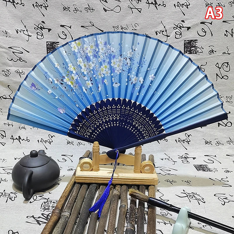 Elegant vintage blue and white Chinese folding hand fan displayed on a wooden stand.