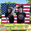 Two men posing in front of an American flag backdrop for a tapestry wall hanging