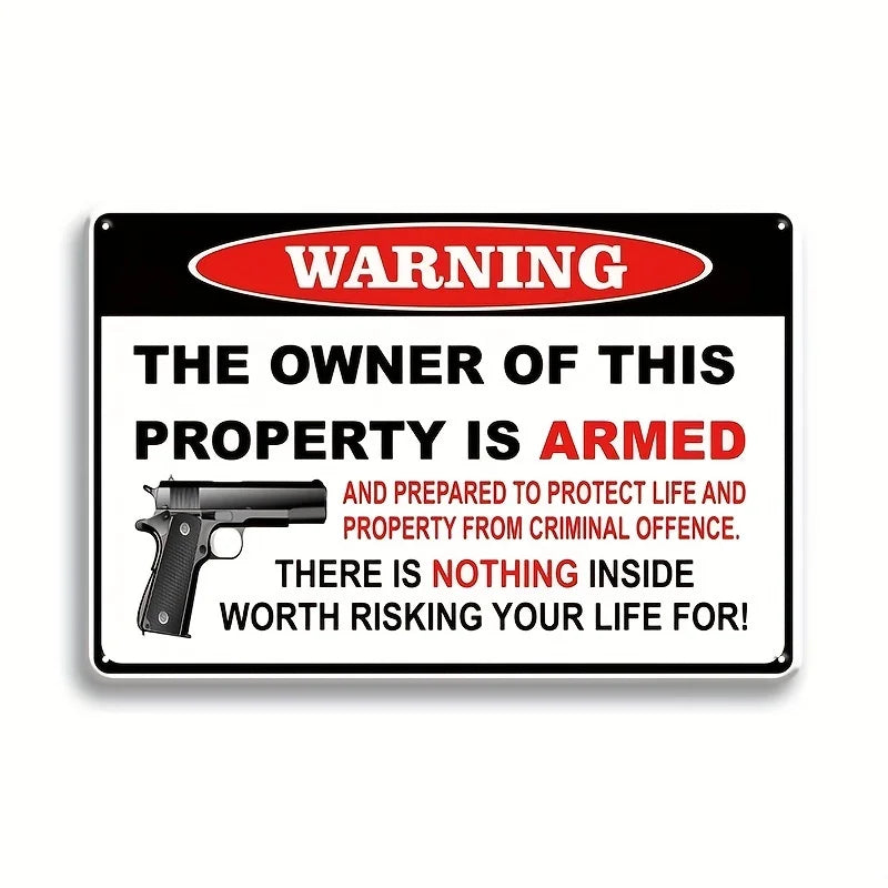 A black and white warning sign with red text stating that the owner of the property is armed and prepared to protect life and