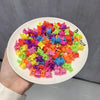A pile of colorful flower and star hair claw clips for kids arranged on a white plate.