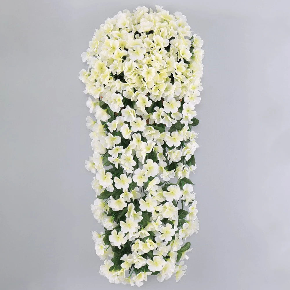 A vertical arrangement of artificial white violet ivy flowers used as a hanging garland for decor.