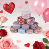 A stack of decorative soy wax candles in various patterns and colors surrounded by pink and red roses and heart-shaped balloo