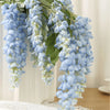 A long, cascading artificial wisteria vine with light blue flowers and green leaves hanging indoors.