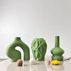 A set of three organic, textured green geometric vases displayed on a white surface.
