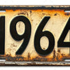 Señal de pared de aluminio vintage con el año 1964 grabado, mostrando signos de envejecimiento y pátina.